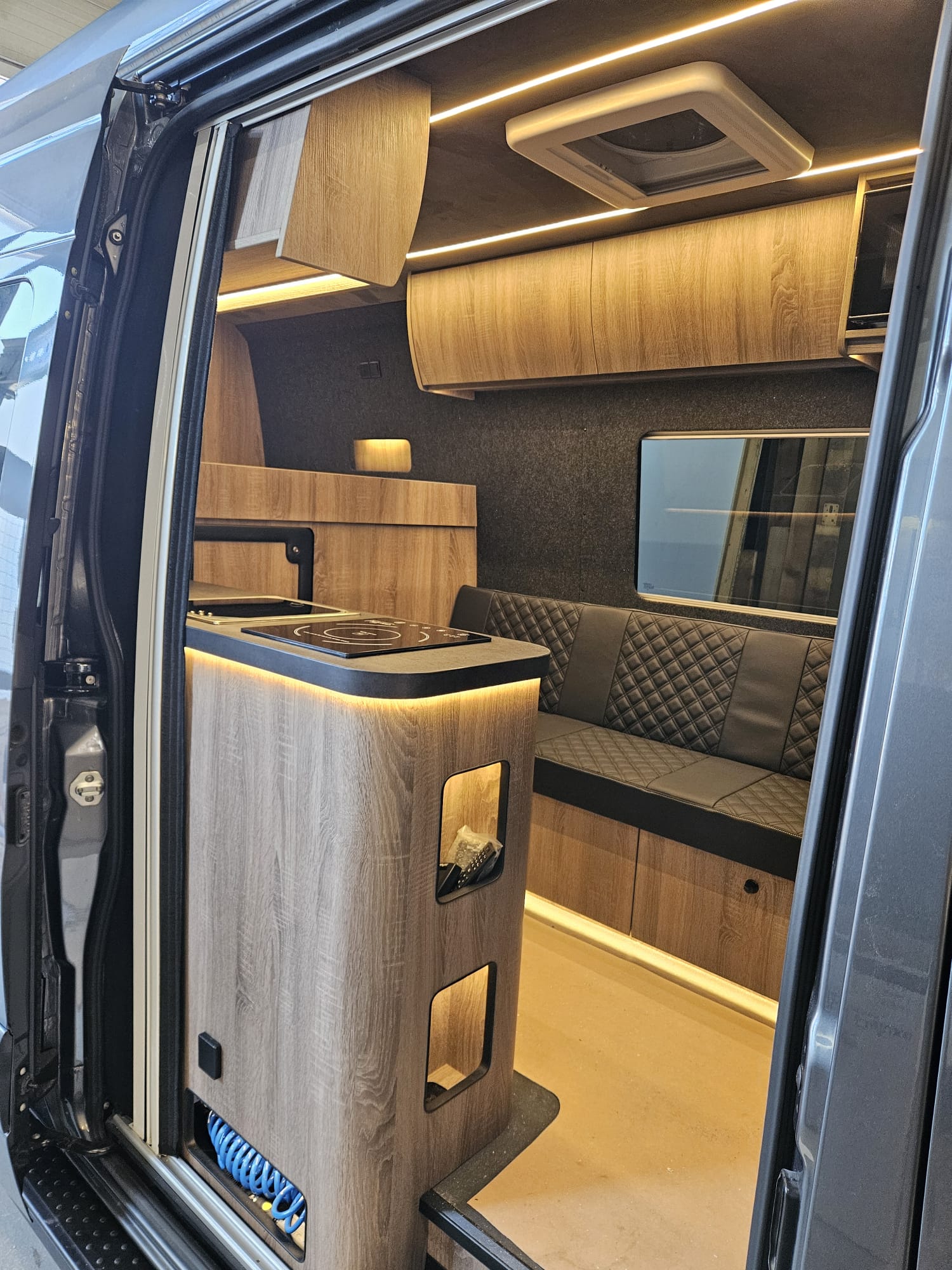 Luxury camper interior with wooden kitchen unit and seating by R-Line Maatwerk