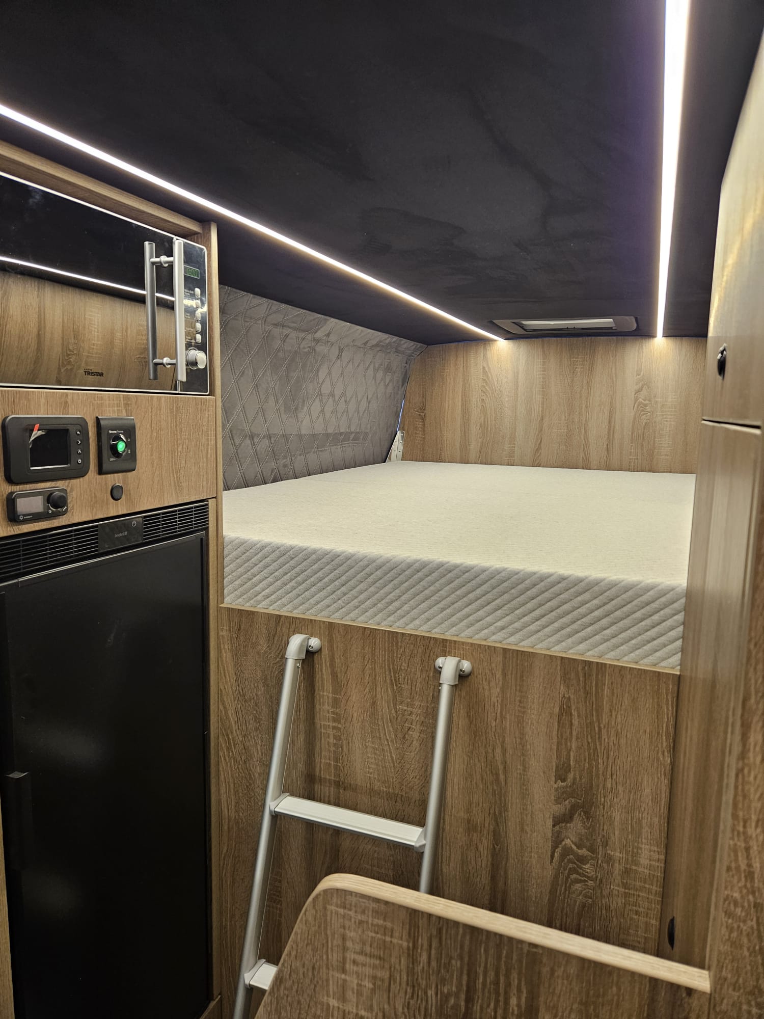 Camper-Schlafbereich mit Leiter und integriertem Kühlschrank